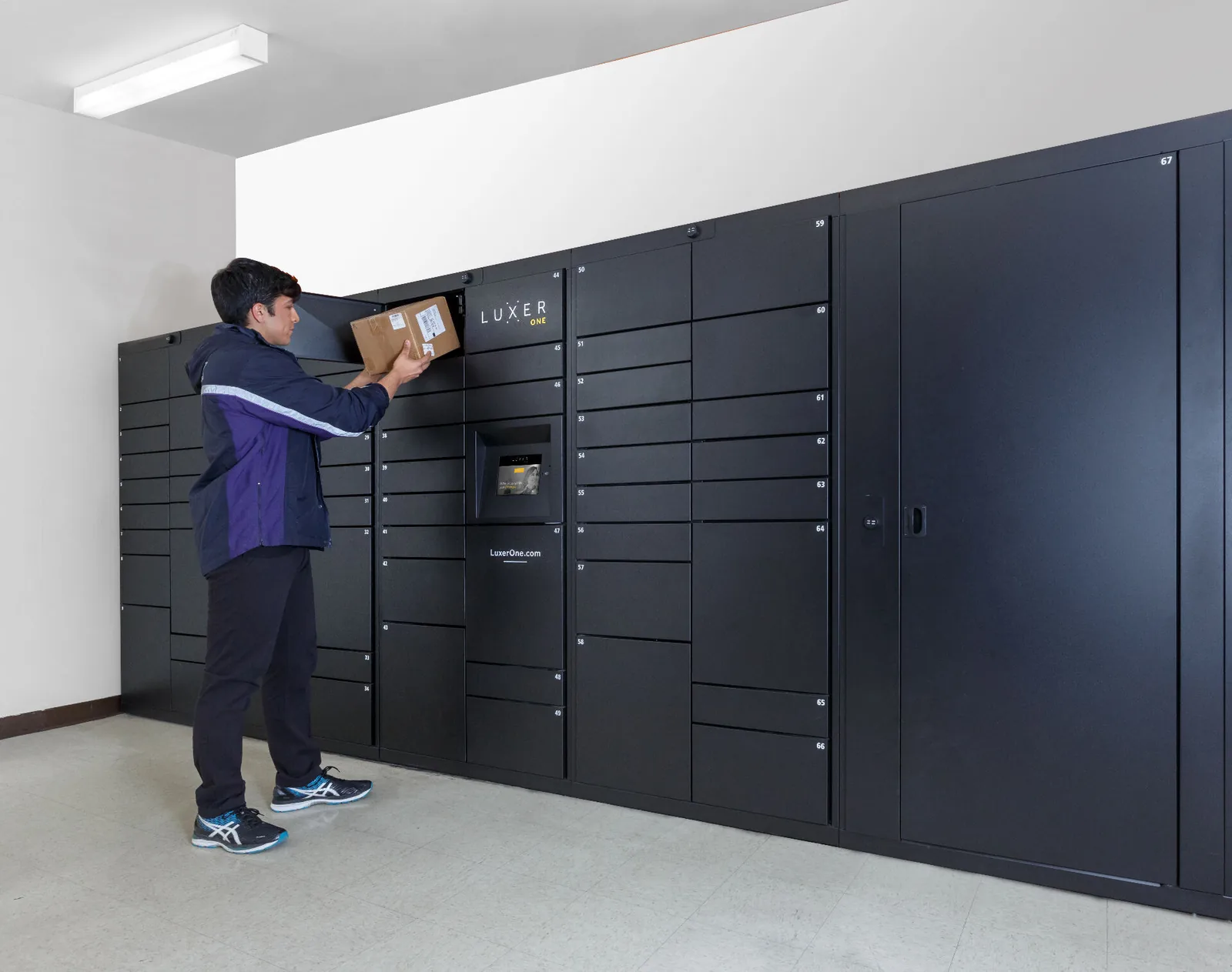 Luxer One indoor electronic package lockers with central touchscreen kiosk in a modern apartment mailroom